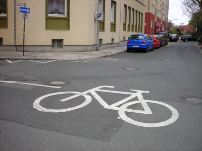 Ein großes weißes Fahrradpiktogramm auf einer Straße.