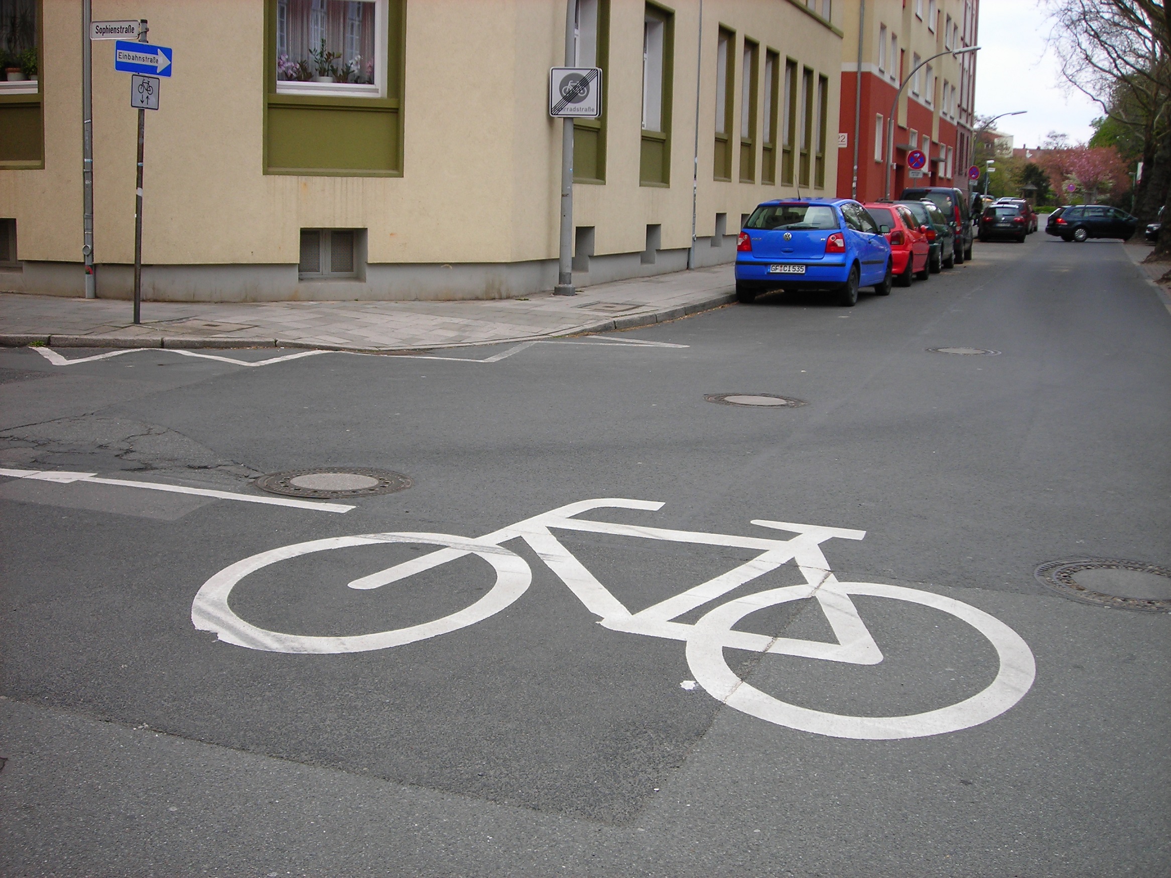 Ein großes weißes Fahrradpiktogramm auf einer Straße.